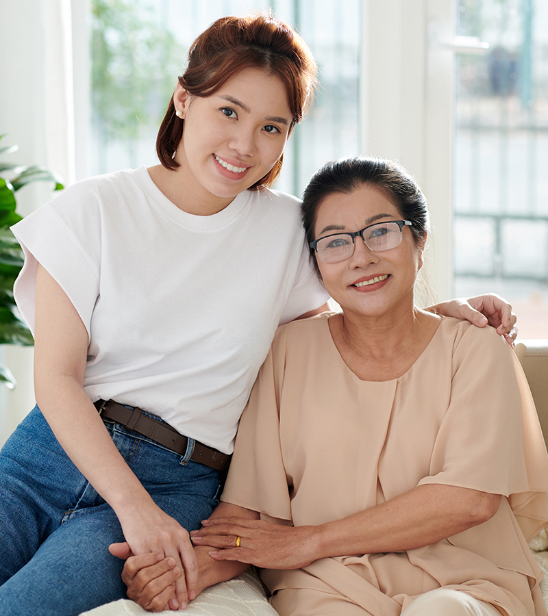 Two asian women sitting on a couch together.
