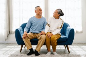 An elderly couple sitting on a blue couch.