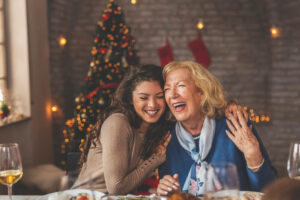 Two women laughing at a christmas dinner table.